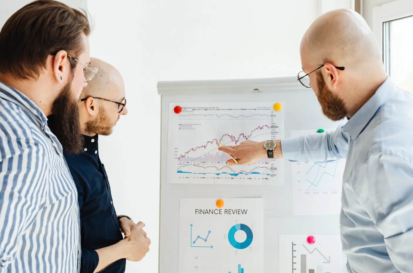 Tres profesionales de finanzas revisan gráficos y datos de desempeño financiero para respaldar decisiones sobre automatización financiera.