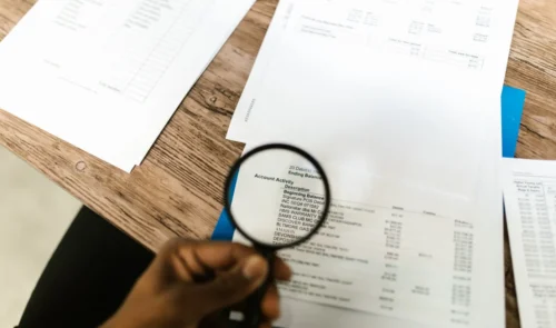 Lupa que resalta la actividad de la cuenta y los detalles de las transacciones en un estado financiero.