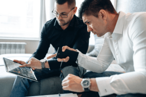 Two finance professionals reviewing financial data on a laptop and tablet during a finance transformation