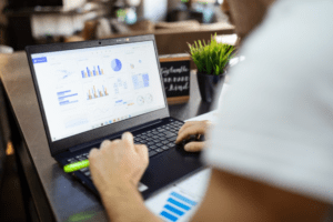 Finance professional analyzing financial performance dashboards on a laptop