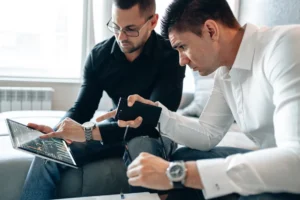 Dos profesionales de finanzas revisan datos financieros en un portátil y una tableta durante un proceso de transformación financiera.