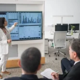the-complete-guide-to-onestream-implementation Finance professional presenting financial dashboards and analytics to a business team during a OneStream implementation discussion.